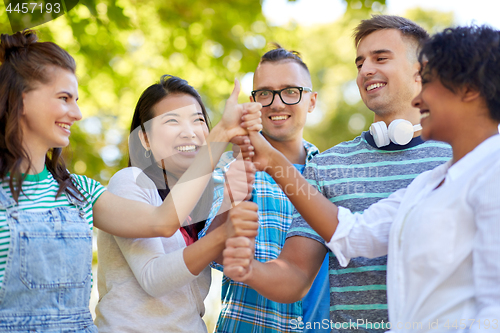 Image of happy friends making thumbs up in park