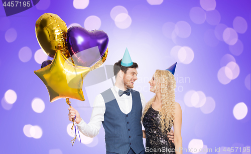 Image of happy couple with party caps and balloons