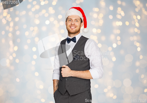 Image of happy man in santa hat and suit on christmas