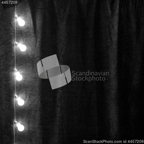 Image of Garland of light bulbs hanging verticaly in the dark room.