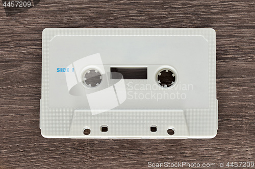 Image of Vintage white audio cassette tape on brown wooden background. Side 1