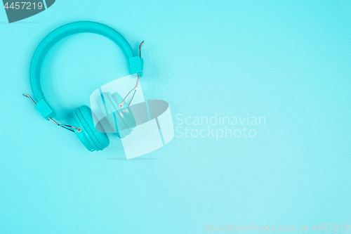 Image of Pastel green headphone on pastel green metal table background.