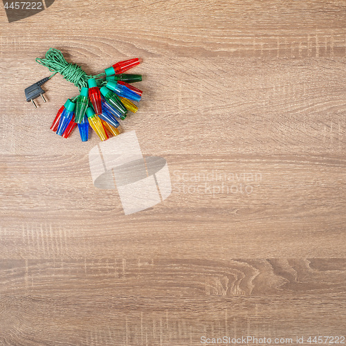 Image of Christmas colorful lights on brown wooden background.