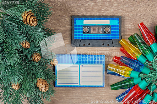 Image of Retro blue audio cassette and christmas decorations on bown wooden background.