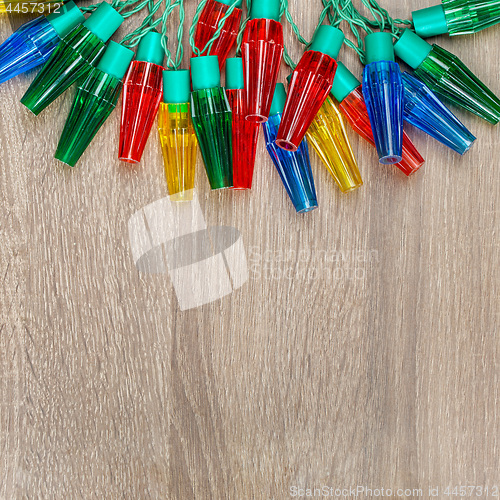 Image of Christmas colorful lights on brown wooden background.