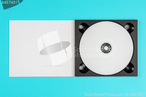 Image of White cd in black case on pastel green background.