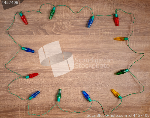 Image of Christmas colorful lights on brown wooden background.