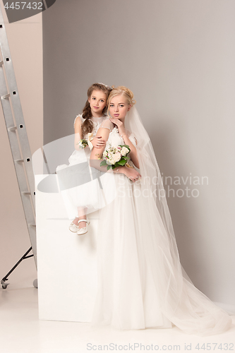 Image of Little pretty girls with flowers dressed in wedding dresses