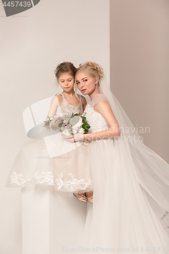 Image of Little pretty girls with flowers dressed in wedding dresses