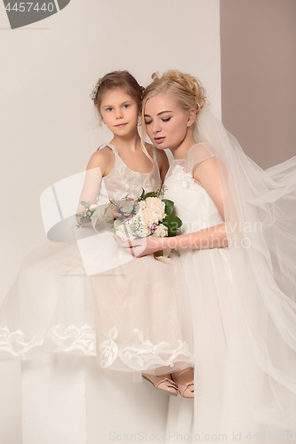 Image of Little pretty girls with flowers dressed in wedding dresses