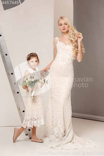 Image of Little pretty girls with flowers dressed in wedding dresses