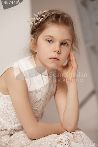 Image of Little pretty girl with flowers dressed in wedding dresses