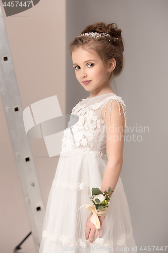 Image of Little pretty girl with flowers dressed in wedding dresses