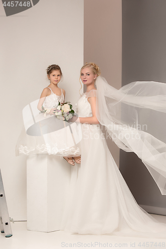 Image of Little pretty girls with flowers dressed in wedding dresses