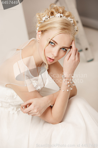 Image of Bride in beautiful dress standing indoors in white studio interior like at home. Trendy wedding style shot. Young attractive caucasian model like a bride tender looking.