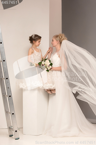 Image of Little pretty girls with flowers dressed in wedding dresses