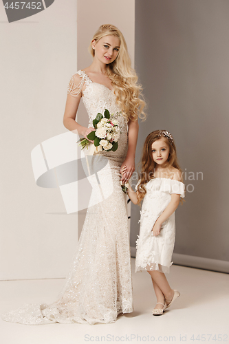 Image of Little pretty girls with flowers dressed in wedding dresses