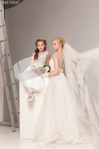 Image of Little pretty girls with flowers dressed in wedding dresses