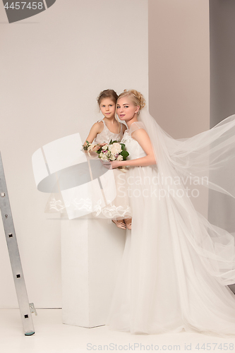 Image of Little pretty girls with flowers dressed in wedding dresses