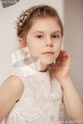 Image of Little pretty girl with flowers dressed in wedding dresses