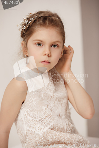 Image of Little pretty girl with flowers dressed in wedding dresses