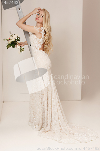 Image of Bride in beautiful dress standing indoors in white studio interior like at home. Trendy wedding style shot. Young attractive caucasian model like a bride tender looking.