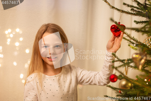 Image of happy girl in red dress decorating christmas tree