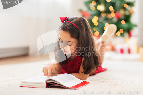 Image of happy girl reading book at home on christmas