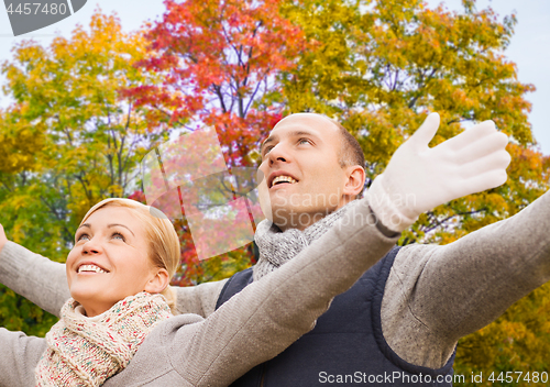 Image of happy couple spreading hands leaves in autumn park