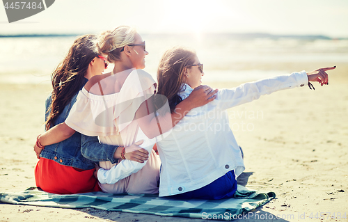 Image of group of smiling women in sunglasses on beach