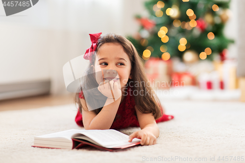 Image of happy girl reading book at home on christmas