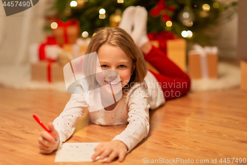 Image of smiling girl writing christmas wish list at home