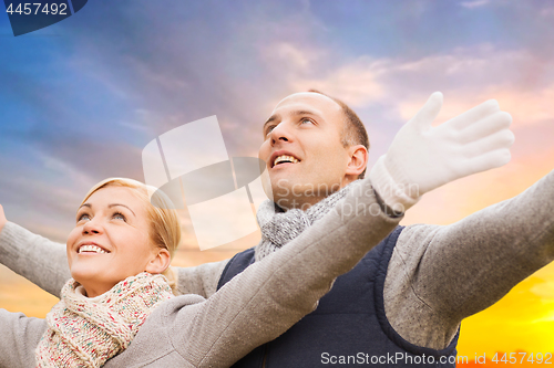 Image of happy couple in autumn clothes over sunset in city