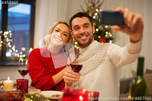 Image of happy couple taking selfie at christmas dinner