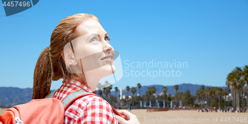 Image of smiling woman with backpack over venice beach