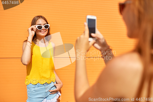 Image of teenage girl photographing friend by smartphone