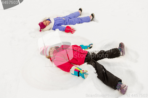 Image of happy little girls making snow angels in winter