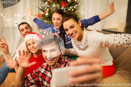 Image of friends celebrating christmas and taking selfie
