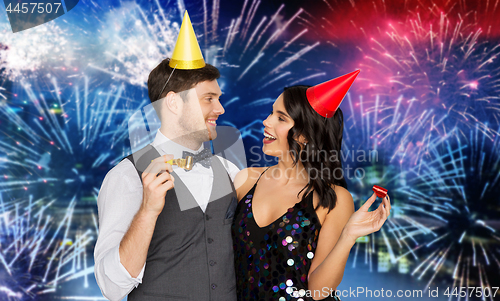 Image of happy couple with party blowers having fun