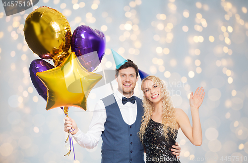 Image of happy couple in party hats with balloons