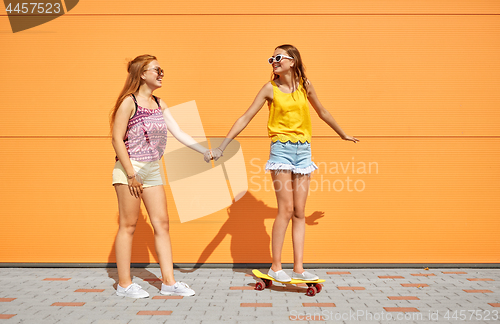 Image of teenage girls riding skateboard on city street