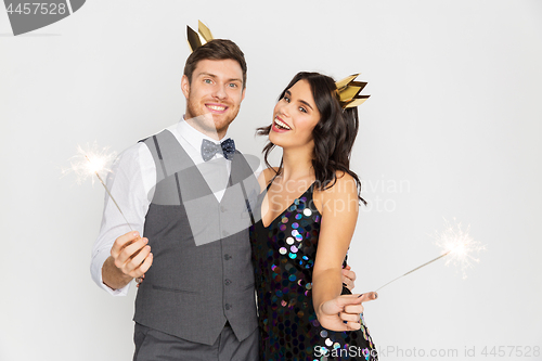 Image of happy couple with crowns and sparklers at party