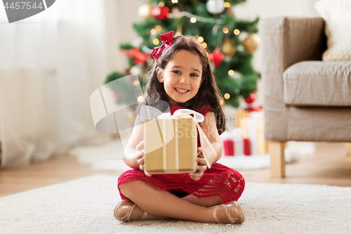 Image of happy girl with christmas gift at home