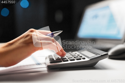 Image of businesswoman with calculator at night office