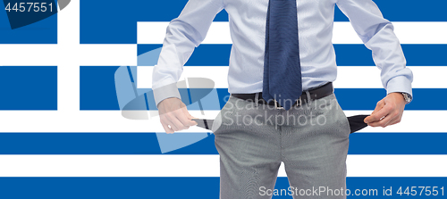 Image of businessman with empty pockets over flag of greece