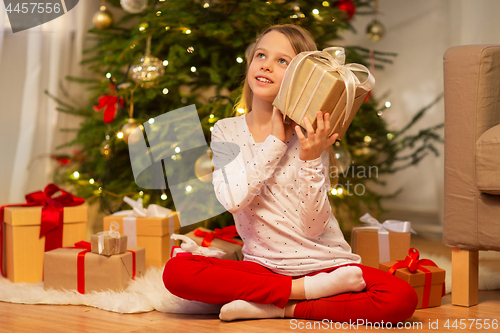 Image of smiling girl with christmas gift at home