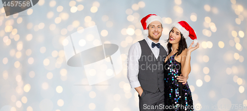Image of happy couple in santa hats at christmas party