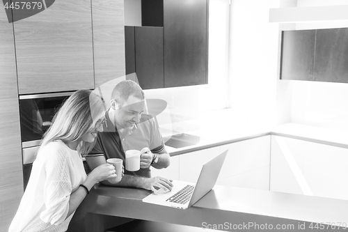 Image of couple drinking coffee and using laptop at home