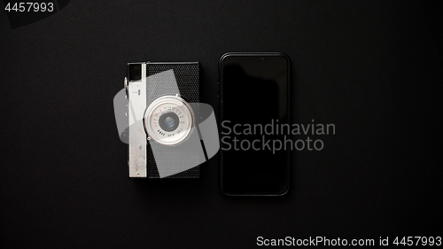 Image of Old retro film camera and modern smartphone on black background