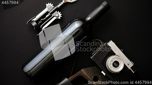 Image of Red wine bottle, corkscrew and old photo camera